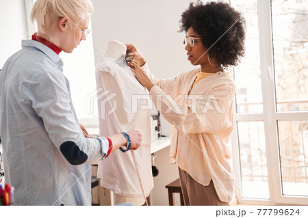 Colleagues standing in front of the mannequin and discussing re sewing process Colleagues standing in front of the mannequin and discussing re sewing process 77799624