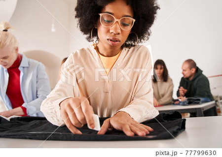 Woman making pattern at the table while working at the recycling workplace Woman making pattern at the table while working at the recycling workplace 77799630