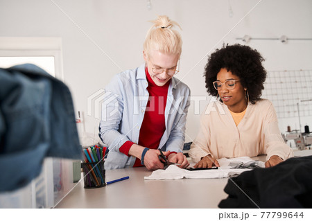 Woman looking attentively at the t shirt and listening ideas from her colleague Woman looking attentively at the t shirt and listening ideas from her colleague 77799644