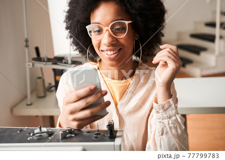 Woman wearing glasses checking messages at her smartphone with pleasure smile Woman wearing glasses checking messages at her smartphone with pleasure smile 77799783