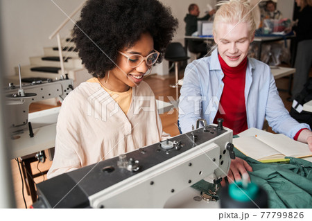 Multiracial female stitching fabric on professional manufacturing machine at workplace Multiracial female stitching fabric on professional manufacturing machine at workplace 77799826
