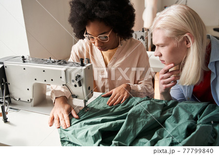 Multiracial seamstress working on the sewing machine while re sewing clothes 77799840