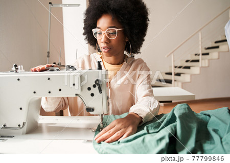 Woman recycling clothes and re sewing it for environmental purposes Woman recycling clothes and re sewing it for environmental purposes 77799846