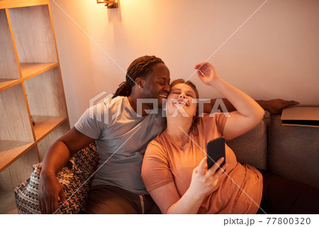 Couple bonding to each other and laughing while making selfie at the smartphone 77800320