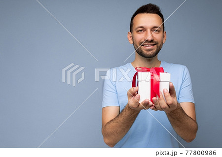Photo shot of handsome positive smiling brunette unshaven young man isolated over blue background Photo shot of handsome positive smiling brunette unshaven young man isolated over blue background 77800986