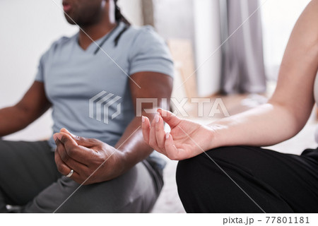 Woman meditating at home in the morning with her multiracial husband and practicing yoga 77801181