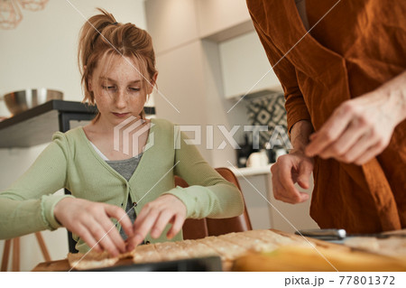 Girl preparing bagels from the dough while helping to her senior grandmother 77801372