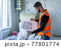 Male worker holding a paper apartment plan indoor before repair room  77801774