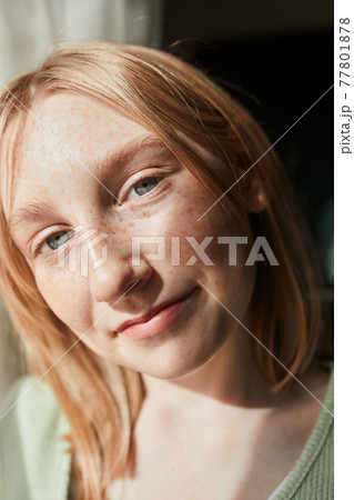 Girl looking at the camera while sitting at the windowsill and enjoying of the good day 77801878