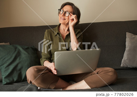 Woman puzzled about something and adjusting her glasses while using laptop 77802026