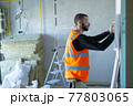 Male worker holding a paper apartment plan indoor before repair room  77803065