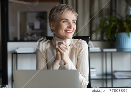 Smiling businesswoman work on laptop looking in distance Smiling businesswoman work on laptop looking in distance 77803392