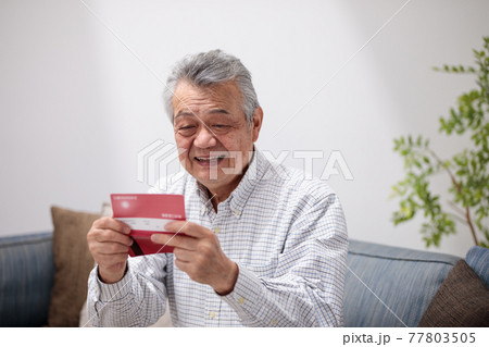 通帳を見て喜ぶシニア男性 通帳を見て喜ぶシニア男性 77803505