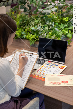 ワクチン接種のお知らせをみる女性のイメージ 77804450