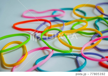 Side view of colorful rubber bands on white. Rainbow elastic rubber bands on white. Selective focus. 77805392