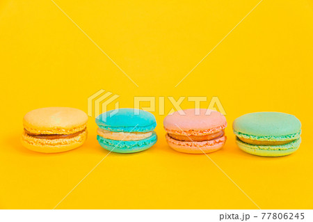Sweet almond colorful unicorn pink blue yellow green macaron or macaroon dessert cake isolated on trendy yellow modern fashion background. French sweet cookie. Minimal food bakery concept Copy space Sweet almond colorful unicorn pink blue yellow green macaron or macaroon dessert cake isolated on trendy yellow modern fashion background. French sweet cookie. Minimal food bakery concept Copy space 77806245