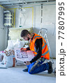 Male worker holding a paper apartment plan indoor before repair room  77807995