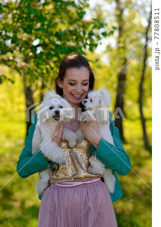 Young woman with her dog. Puppy white dog is running with it's owner. Concept about friendship, animal and freedom. 77808511