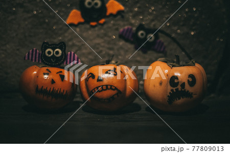 small pumpkins with different faces stand on a wooden shelf, in the background are handmade bats made of felt. Halloween Attributes 77809013