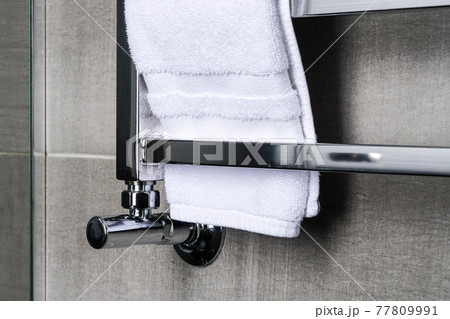 fragment of a chrome steel bathroom towel dryer on the gray anthracite tile wall 77809991