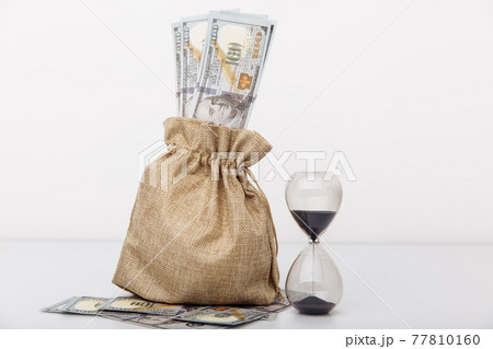 Hourglass with money bag on white background. Finance saving and investment concept. Hourglass with money bag on white background. Finance saving and investment concept. 77810160