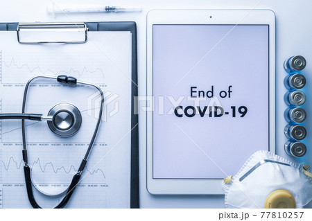 End of pandemic. Syringe with needle, hospital healthcare charts, doctor stethoscope and white tablet with text on screen for medical equipment background. End of COVID concept. End of pandemic. Syringe with needle, hospital healthcare charts, doctor stethoscope and white tablet with text on screen for medical equipment background. End of COVID concept. 77810257