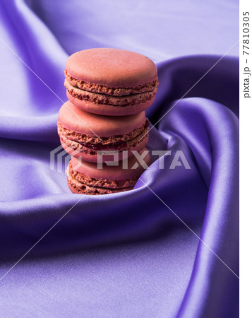Pastel pink french macaroons on purple silk fabric background 77810305