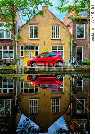 Red car on canal embankment in street of Delft. Delft, Netherlands 77810561