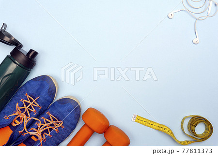 Sport concept with sport equipment composition. Sneakers, dumbbells, bottle of water on bright blue background 77811373