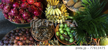 Exotic and tropical fruits on the market of Asia, Thailand, Vietnam. Mini bananas, longan, pitaya, Dragon Fruit, papaya. 77813475