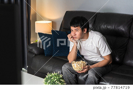 bored man watching TV on sofa at night bored man watching TV on sofa at night 77814719