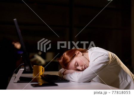 Young caucasian female sleeping at work place in office at night, need more rest 77818055