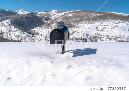 Black freestanding residential mailbox against deep snow in Park City Utah 77820587