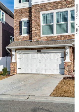 Three storey house with stone brick wall and hinged garage door at the facade Three storey house with stone brick wall and hinged garage door at the facade 77820606