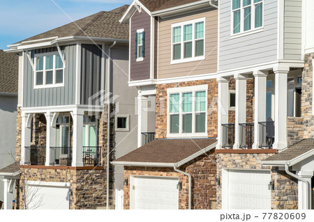 Townhouses with balconies and garages at the facade on a sunny day landscape 77820609