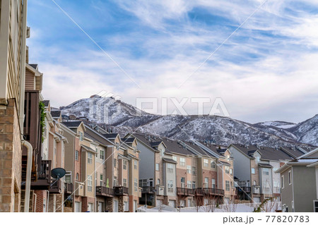 Mountain peak and townhouses against cloudy blue sky background in winter 77820783