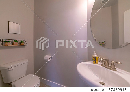 Clean bathroom interior with toilet sink and round wall mounted mirror 77820913