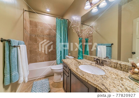 Bathroom interior with warm toned tiles rectangular bathtub toilet and vanity Bathroom interior with warm toned tiles rectangular bathtub toilet and vanity 77820927