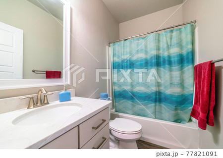 Interior of bathroom with toilet beside bathtub and shower with blue curtain Interior of bathroom with toilet beside bathtub and shower with blue curtain 77821091