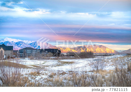 Sunset scenery with houses in the snowy valley overlooking lake and mountain. Sunset scenery with houses in the snowy valley overlooking lake and mountain. 77821115