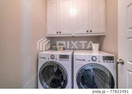 Interior of laundry room with appliances and wall mounted wooden cabinet 77822491