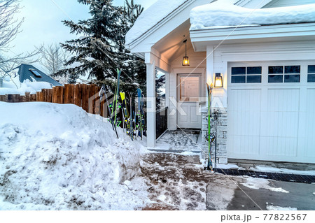 Glass paned door and garage doors of a white home on a snowy mountain town Glass paned door and garage doors of a white home on a snowy mountain town 77822567