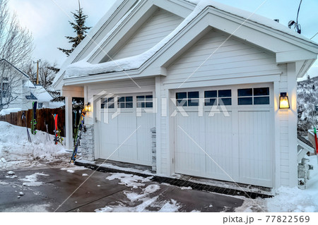 Home with white exterior walls and glass paned garage doors on a mountain town 77822569