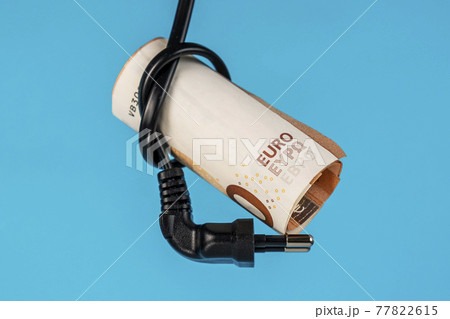 Cash Euro money and electrical plug close up on a blue background. Creative concept of energy efficiency and financial cost of electricity consumption. Home budget idea Cash Euro money and electrical plug close up on a blue background. Creative concept of energy efficiency and financial cost of electricity consumption. Home budget idea 77822615