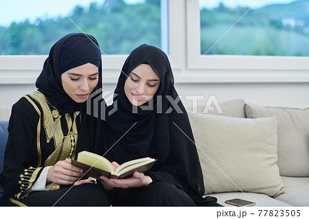 Portrait of young muslim women reading Quran in modern home. 77823505