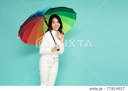 Young happy Asian woman holding colorful umbrella isolated on green background 77824027