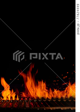 Empty hot barbecue BBQ grill grid with burning fire, sparks and smoldering charcoal on black background. Cooking concept. Close up, copy space 77824449