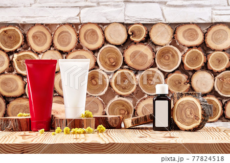 Two colorful cosmetic tubes and brown plastic bottle with branding area, small buds of blooming yellow flowers on wooden surface. Close up, copy space Two colorful cosmetic tubes and brown plastic bottle with branding area, small buds of blooming yellow flowers on wooden surface. Close up, copy space 77824518