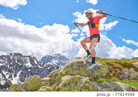 Man athlete jumps between the stones during a trail workout in the mountains Man athlete jumps between the stones during a trail workout in the mountains 77824998