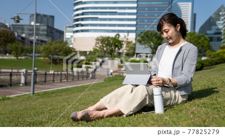 外でリモートワークをする若い女性 外でリモートワークをする若い女性 77825279